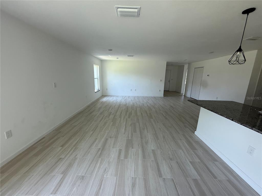 An open-concept living area features light wood-look tile flooring and a kitchen island with granite countertops — 2408 VAN LEER AVENUE, NORTH PORT, FL