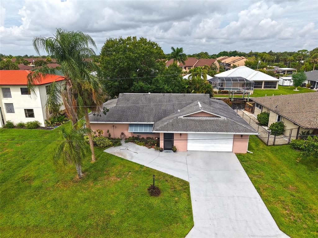 An aerial view shows a single-story pink house with a gray roof and concrete driveway — 7228 REYMOOR DRIVE, NORTH FORT MYERS, FL
