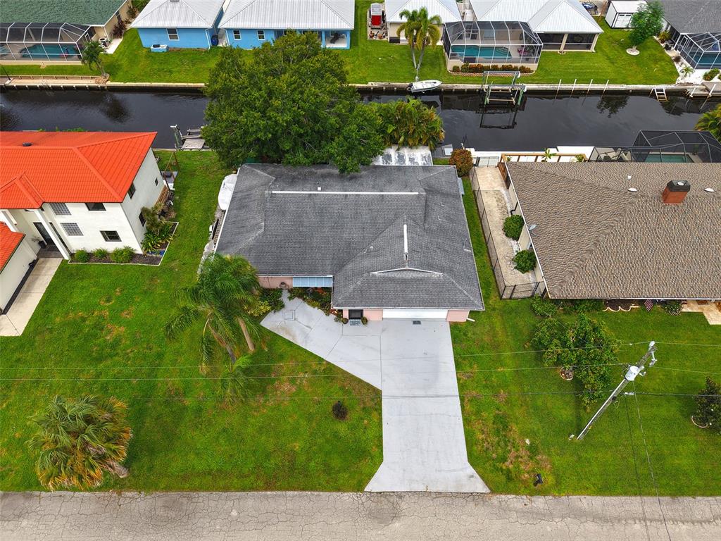 An aerial view shows a single-story house with a gray roof, driveway, and canal access — 7228 REYMOOR DRIVE, NORTH FORT MYERS, FL
