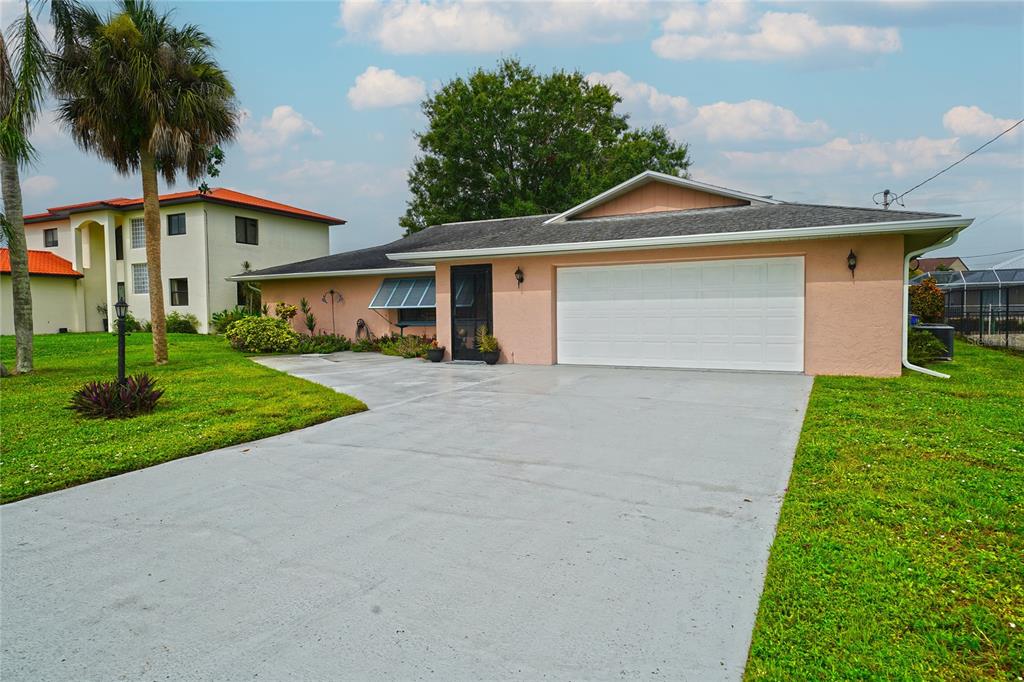 A single-story peach-colored house with a white garage door and a concrete driveway — 7228 REYMOOR DRIVE, NORTH FORT MYERS, FL