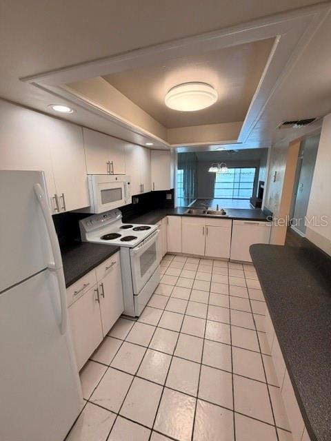 A kitchen features white cabinets, black countertops, white appliances, and white tiled flooring — 4109 FAIRVIEW VISTA POINT UNIT 315, ORLANDO, FL