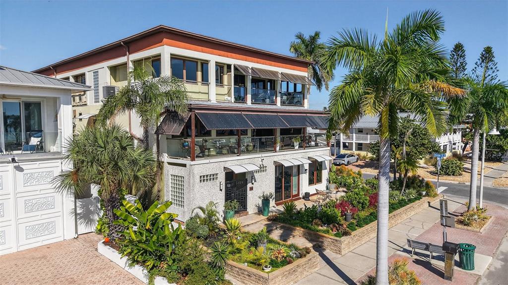An exterior view of a three-story building with balconies, palm trees, and a landscaped yard — 5659 SHORE BOULEVARD S, GULFPORT, FL