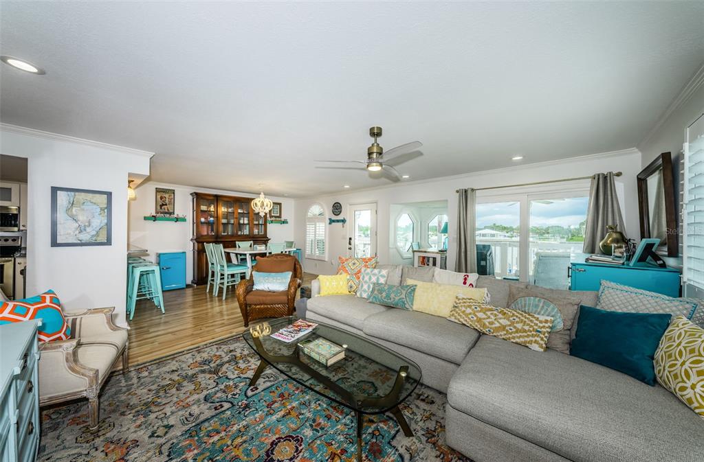 A living room with a gray sectional sofa, a glass coffee table, and dining area — 20019 GULF BOULEVARD UNIT 9, INDIAN SHORES, FL
