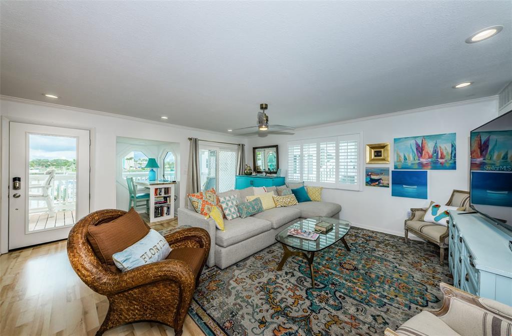 A living room features a sectional sofa, wicker chair, glass coffee table, and coastal decor — 20019 GULF BOULEVARD UNIT 9, INDIAN SHORES, FL