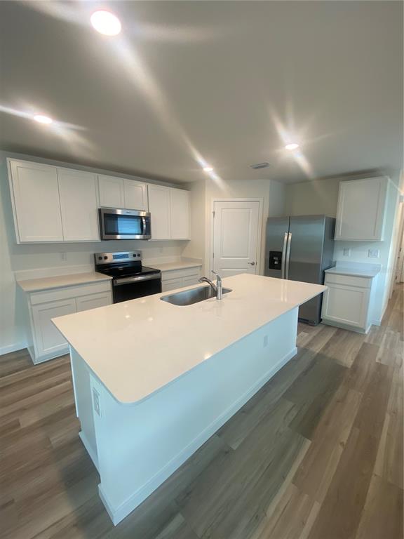 A modern kitchen features white cabinets, stainless steel appliances, a center island, and wood-look flooring — 11511 MEMORIAL DRIVE, BROOKSVILLE, FL