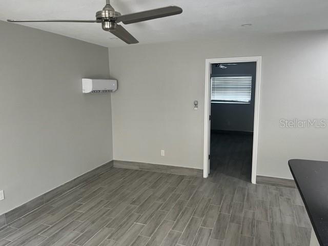 A room with gray walls, wood-look tile flooring, a ceiling fan, and a wall-mounted air conditioner — 1605 PASS A GRILLE WAY UNIT 2, ST PETE BEACH, FL