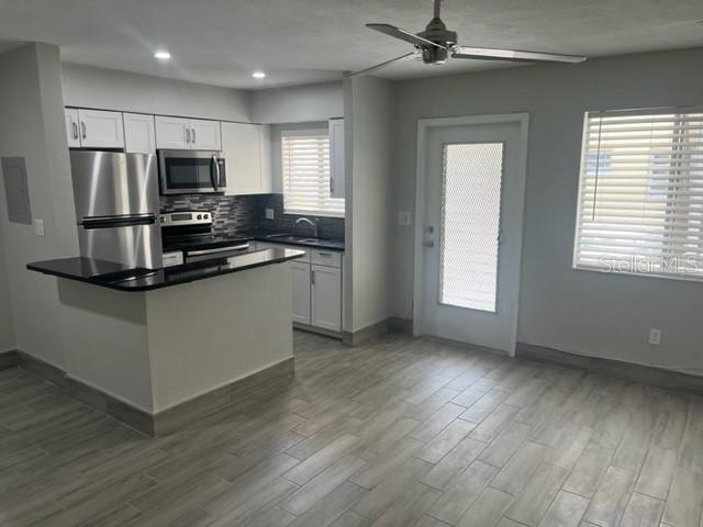 A kitchen with white cabinets, stainless steel appliances, and light wood-look tile flooring — 1605 PASS A GRILLE WAY UNIT 2, ST PETE BEACH, FL