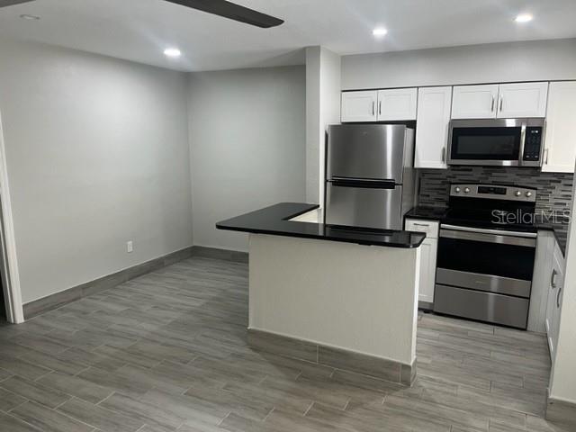 A kitchen with stainless steel appliances, white cabinets, and gray wood-look tile flooring — 1605 PASS A GRILLE WAY UNIT 2, ST PETE BEACH, FL