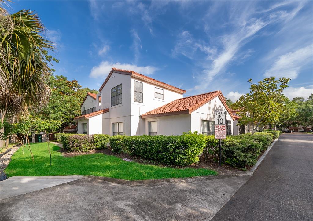 A two-story white stucco building with a red tile roof sits beside a paved road — 520 VIA VERONA LANE UNIT 203, ALTAMONTE SPRINGS, FL