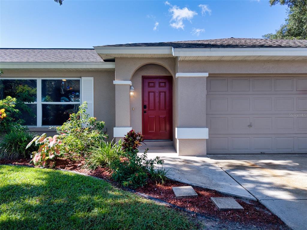 The exterior of a house features a red front door, a garage, and landscaping — 6305 61ST STREET E, PALMETTO, FL