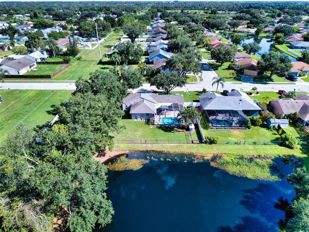 An aerial view shows two houses with screened-in pools situated along a small lake — 6305 61ST STREET E, PALMETTO, FL
