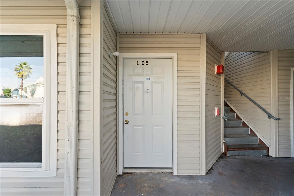 The exterior view shows a white front door labeled 105 next to a concrete staircase — 2508 WOODGATE BOULEVARD UNIT 105, ORLANDO, FL