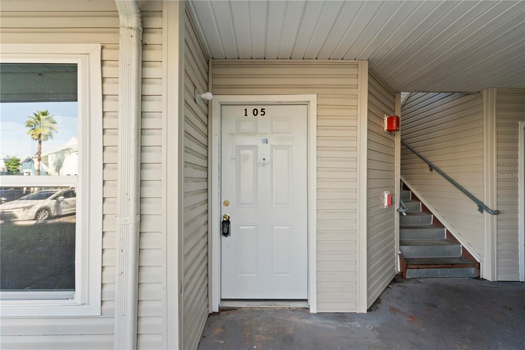 The exterior view shows a white front door labeled 105 next to a concrete staircase — 2508 WOODGATE BOULEVARD UNIT 105, ORLANDO, FL