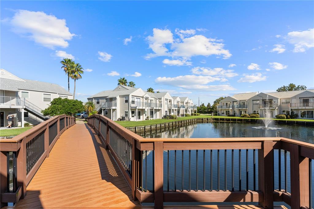 A wooden footbridge overlooks a pond with a fountain and multi-story apartment buildings — 2508 WOODGATE BOULEVARD UNIT 105, ORLANDO, FL