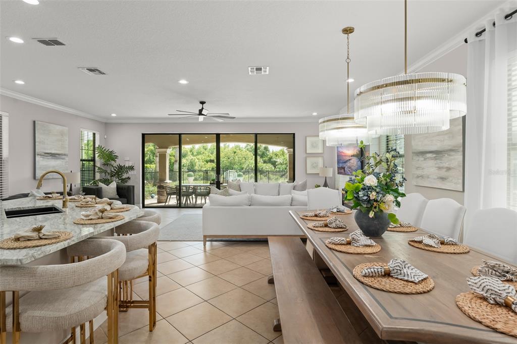 An open-concept dining and kitchen area features a large island, wooden table, and sliding glass doors — 717 DESERT MOUNTAIN COURT, REUNION, FL