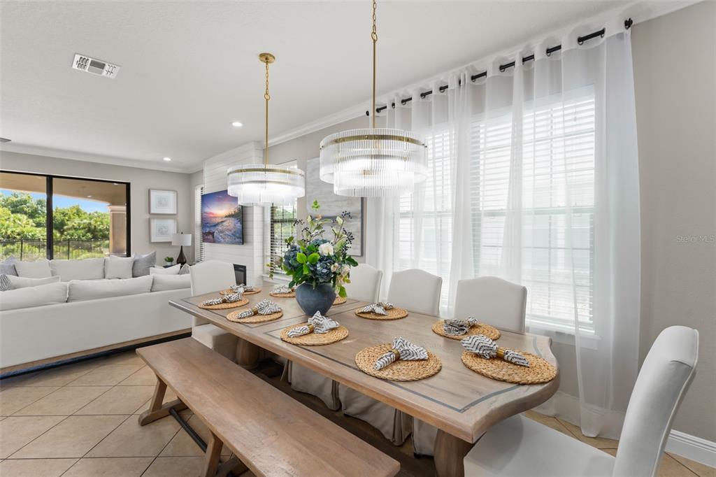 A dining room features a wooden table with a bench, chairs, and two glass chandeliers — 717 DESERT MOUNTAIN COURT, REUNION, FL