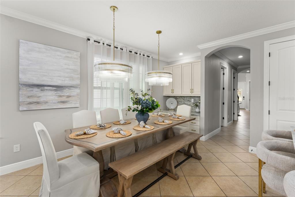 A dining room features a wooden table with a bench, upholstered chairs, and two pendant lights — 717 DESERT MOUNTAIN COURT, REUNION, FL