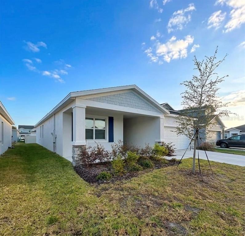 A single-story house with a white stucco exterior, stone accents, and a front-facing garage — 1623 MARKSMAN ROAD, EAGLE LAKE, FL