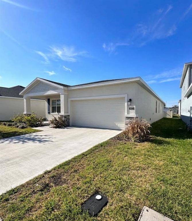 A single-story house with a white stucco exterior, a two-car garage, and a concrete driveway — 1623 MARKSMAN ROAD, EAGLE LAKE, FL