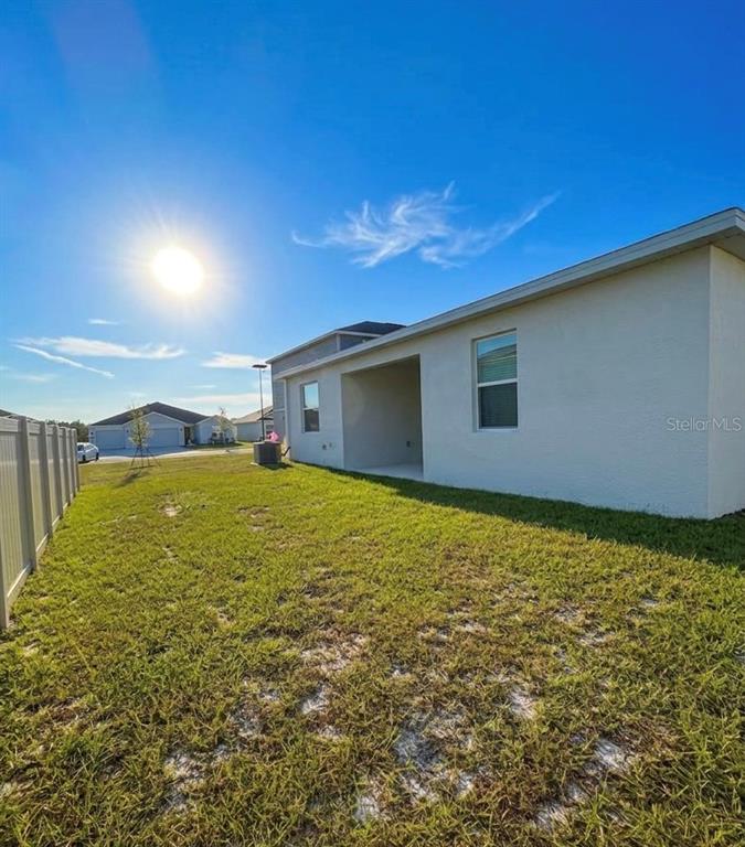 A view of a backyard with a tan house, a covered patio, and a fence — 1623 MARKSMAN ROAD, EAGLE LAKE, FL
