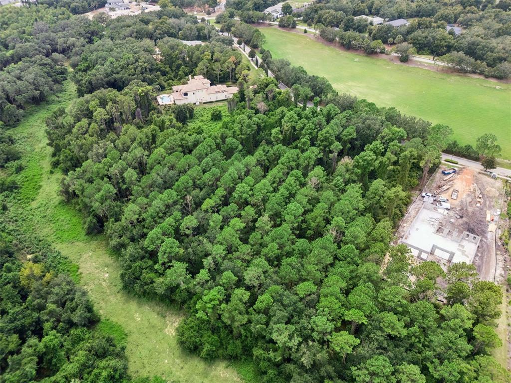 An aerial view shows a wooded lot with a house under construction and nearby residences — 17131 ETRUSCAN LANE, MONTVERDE, FL