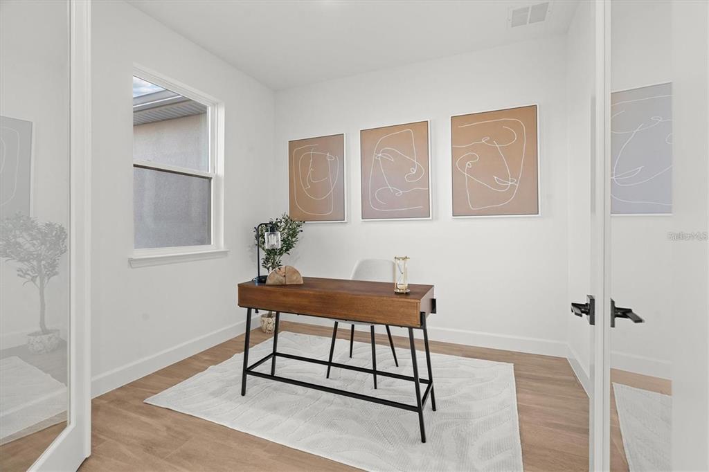 A home office features a wooden desk, three line-art wall prints, and light wood flooring — 18924 NORTHROP STREET, ORLANDO, FL