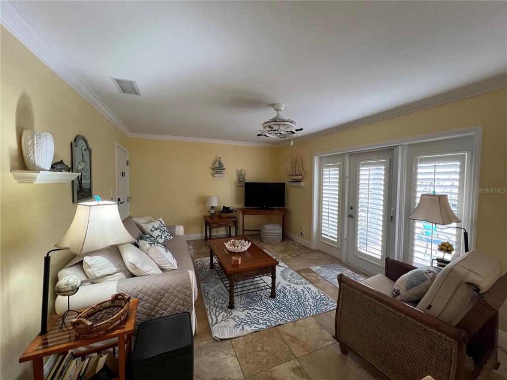 A living room with yellow walls, tile flooring, a sofa, and nautical-themed decor — 5164 BEACH DRIVE SE UNIT B furnished, ST PETERSBURG, FL