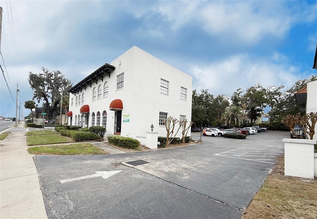 A two-story white stucco building with arched windows and red awnings sits beside a parking lot — 818 E SILVER SPRINGS BOULEVARD, OCALA, FL