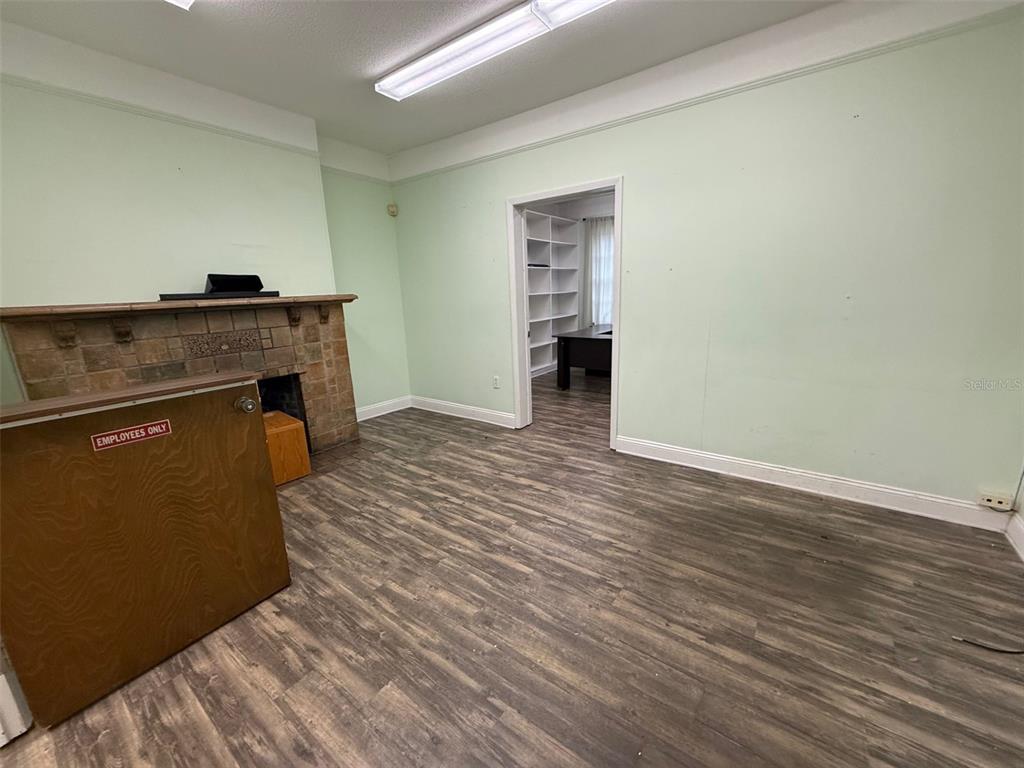 A room with light green walls, a stone fireplace, and wood-look flooring — 818 E SILVER SPRINGS BOULEVARD, OCALA, FL