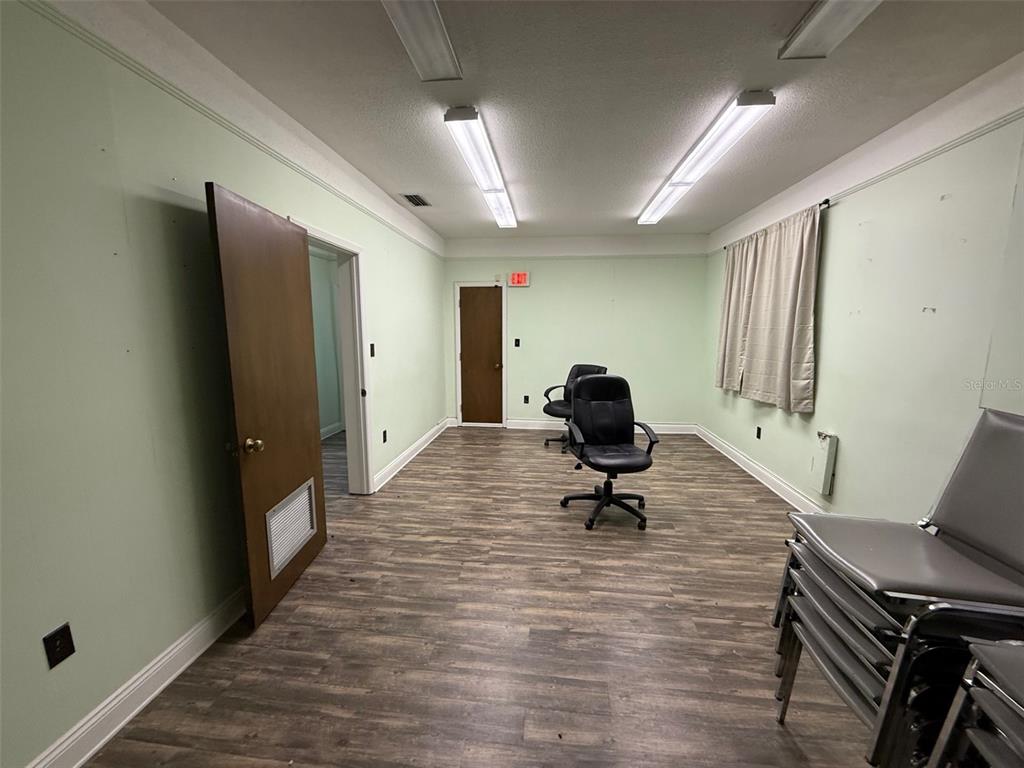 An office room with light green walls, wood-look flooring, two rolling chairs, and fluorescent lighting — 818 E SILVER SPRINGS BOULEVARD, OCALA, FL