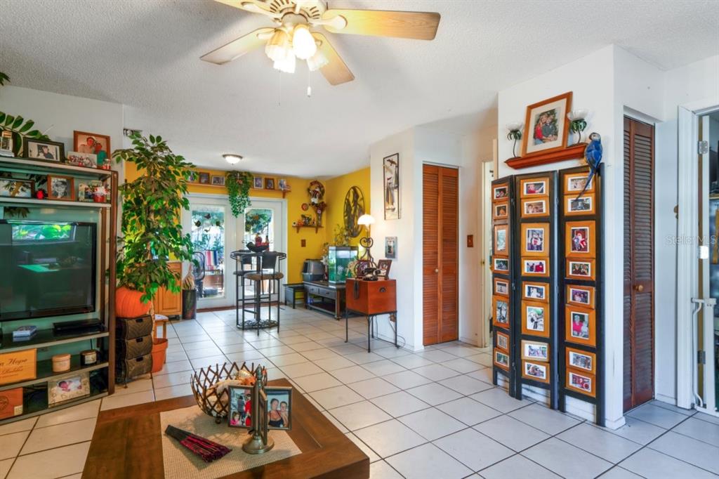 A living room with white tile floors, yellow walls, a ceiling fan, and a photo screen — 2005 HUDSON CT, OLDSMAR, FL