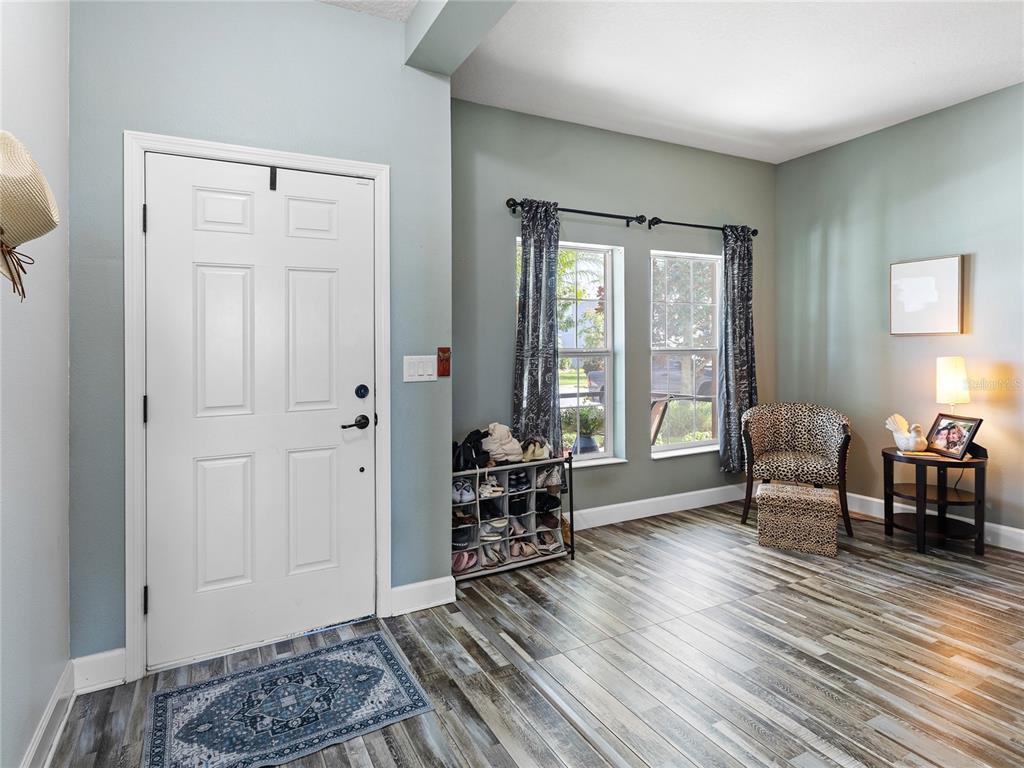 An entryway features a white door, wood-look tile flooring, two windows, and a small seating area — 11323 80TH STREET E, PARRISH, FL