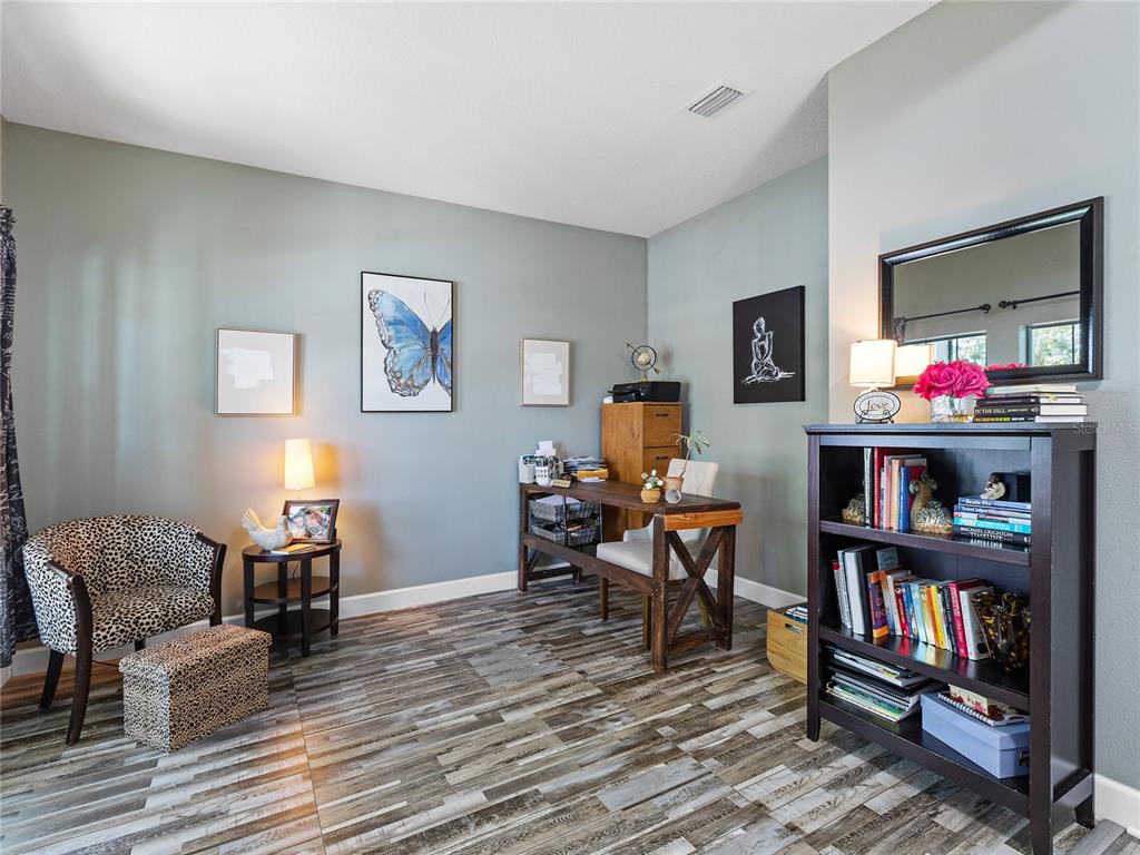 A home office features a wooden desk, a bookshelf, and a leopard-print chair on wood-look tile — 11323 80TH STREET E, PARRISH, FL