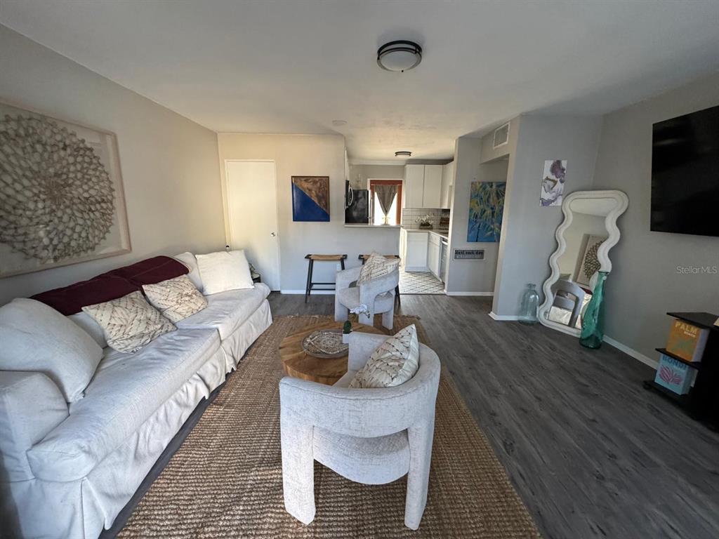 A living room features a white sofa, two armchairs, a jute rug, and an adjacent kitchen — 151 N ORLANDO AVENUE UNIT 118, WINTER PARK, FL