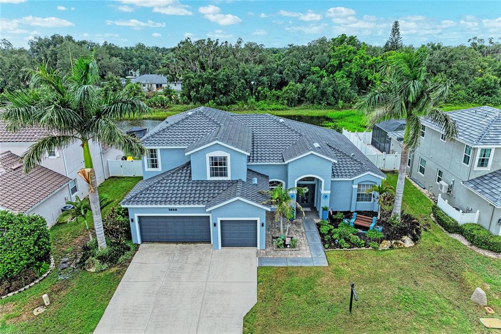 An aerial view shows a blue two-story house with a tile roof and a concrete driveway — 1656 PINYON PINE DR, SARASOTA, FL