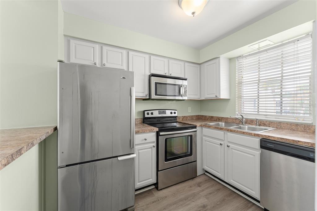 A kitchen with white cabinets, stainless steel appliances, and light-colored countertops — 1250 S DENNING DR Unit 233, WINTER PARK, FL