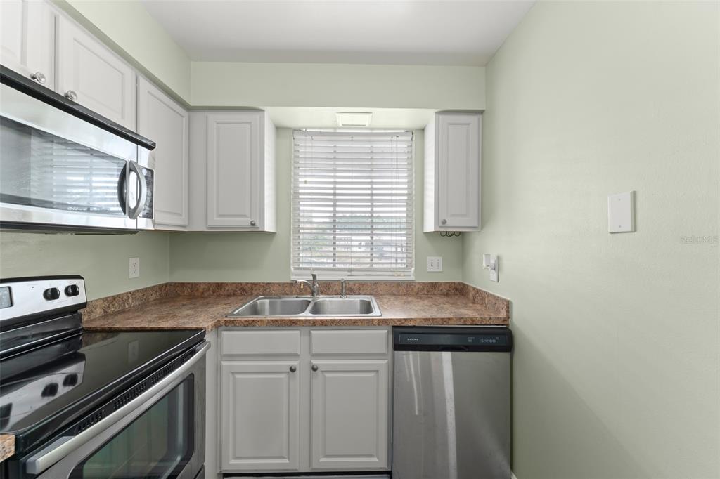 A kitchen with light gray cabinets, stainless steel appliances, and a window above the sink — 1250 S DENNING DR Unit 233, WINTER PARK, FL