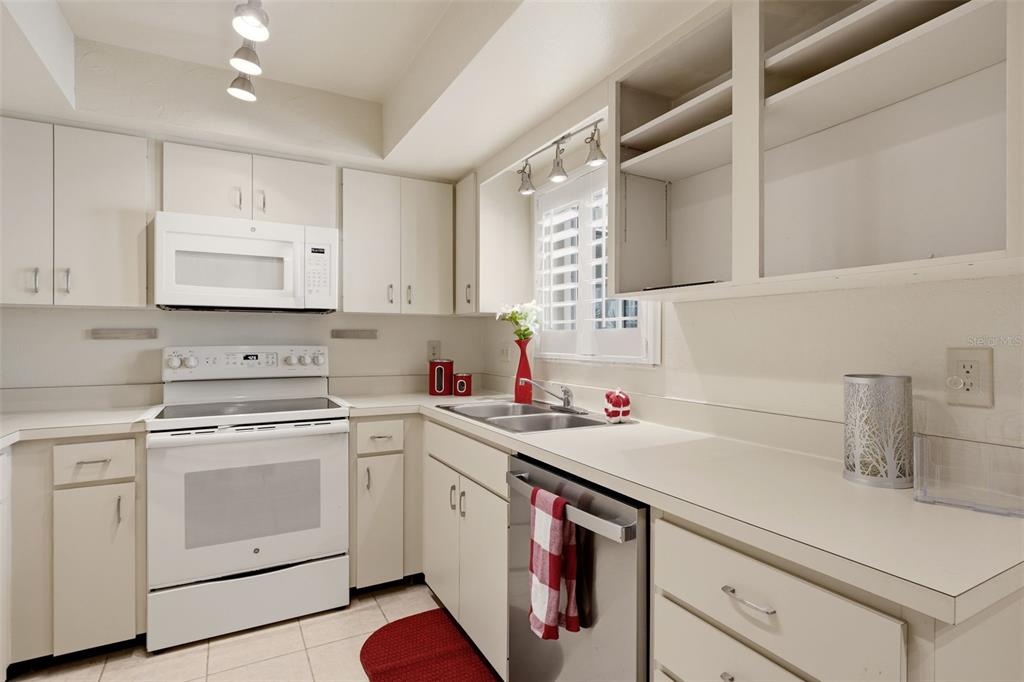 A living room with tile flooring, white walls, a ceiling fan, and patterned furniture — 6132 29TH AVENUE W UNIT 6132, BRADENTON, FL