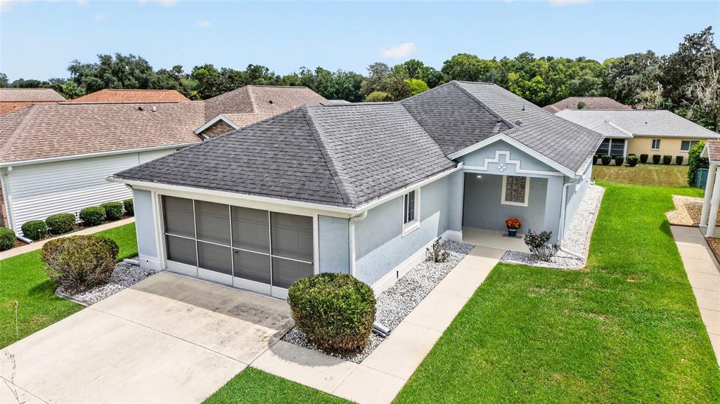An exterior view of a light blue single-story house with a screened-in garage and lawn — 1923 NW 50TH CIRCLE, OCALA, FL