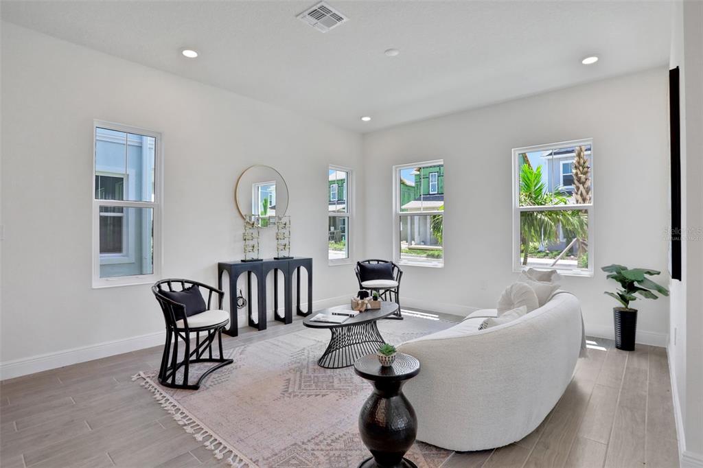 A bright living room features white walls, light wood-look tile flooring, and modern furniture — 9135 WALCOTT LANE, LAKEWOOD RANCH, FL