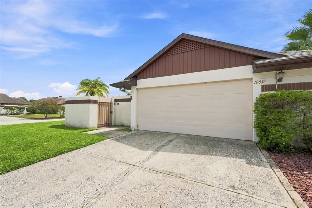 A concrete driveway leads to a single-car garage with a beige door and brown trim — 10836 VENICE CIRCLE, TAMPA, FL