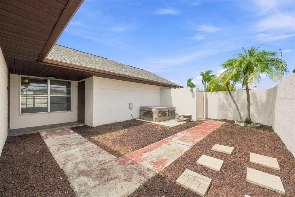 A fenced backyard features a concrete patio, a hot tub, and a palm tree — 10836 VENICE CIRCLE, TAMPA, FL
