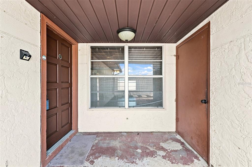 A covered entryway features a brown front door, a storage closet, and a central window — 10836 VENICE CIRCLE, TAMPA, FL