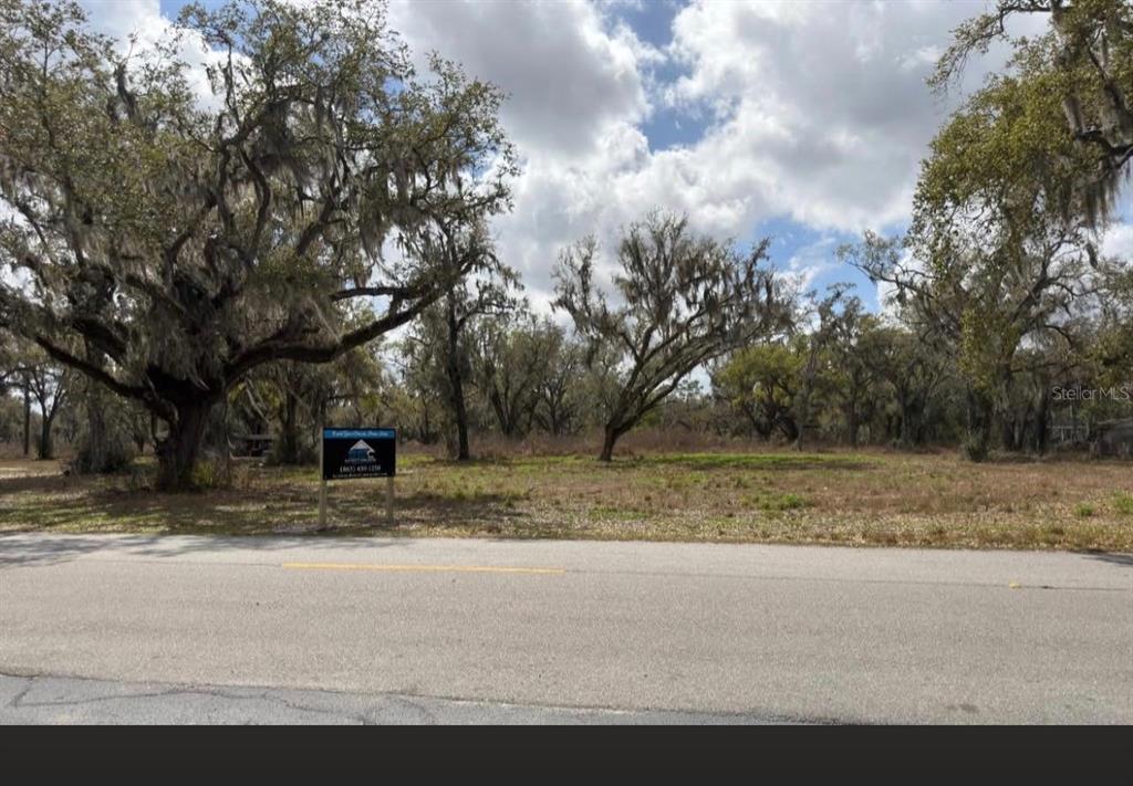 A vacant, tree-covered lot sits behind a paved road with a real estate sign — GASKIN ROAD, BARTOW, FL