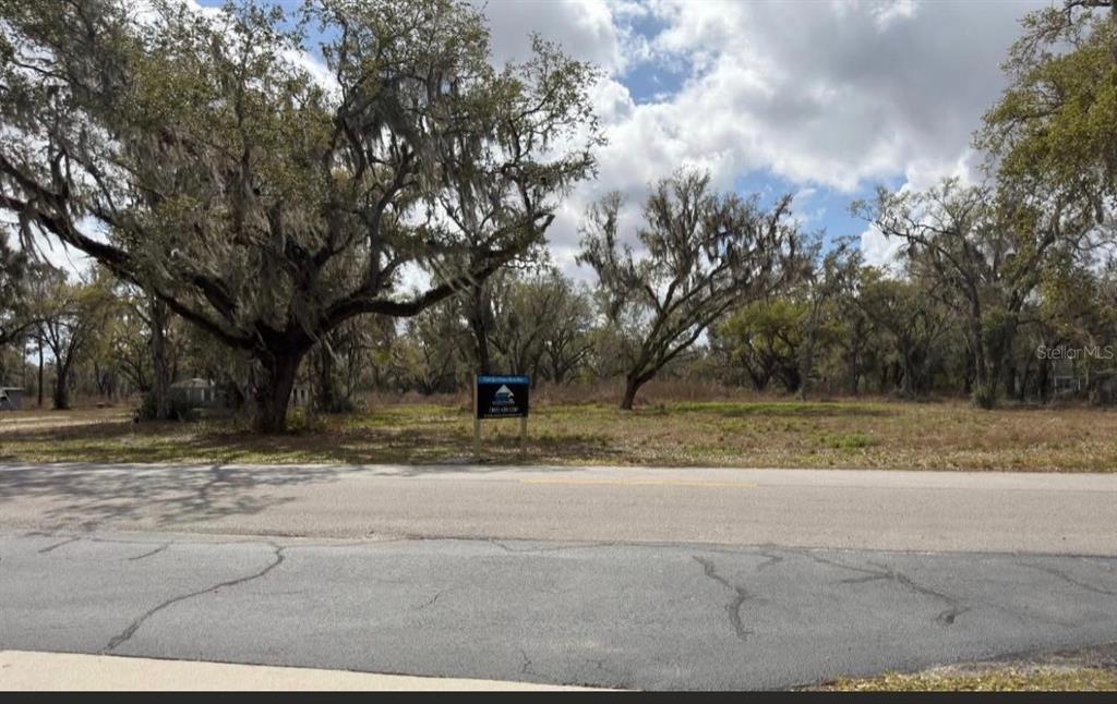 A vacant, grassy lot with several large oak trees sits behind a paved road — GASKIN ROAD, BARTOW, FL