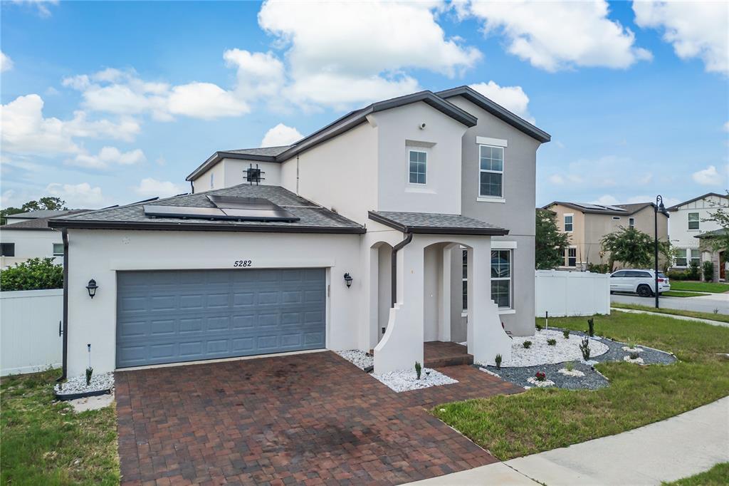 A two-story house with a brick driveway, gray garage door, and white stucco exterior — 5282 PAVIA DRIVE, ST CLOUD, FL