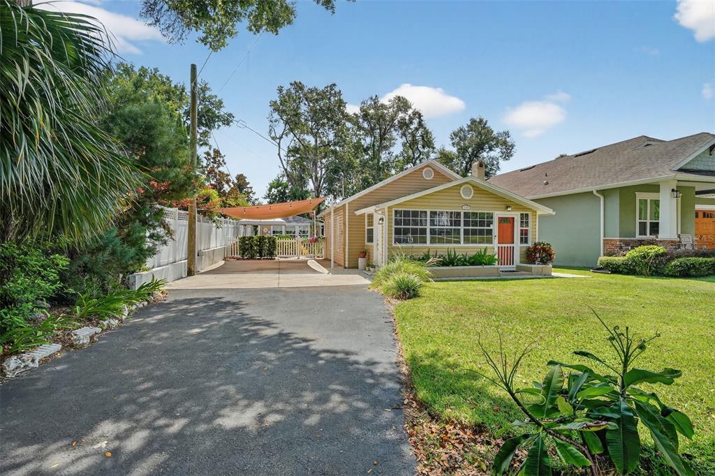 A single-story house with tan siding, a front porch, and a paved driveway — 418 E 10TH AVENUE, MOUNT DORA, FL