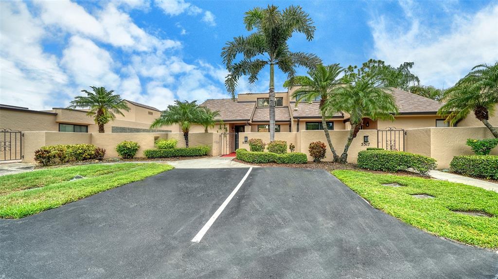 A tan stucco house with a palm tree, a paved driveway, and a low wall — 5315 MYRTLE UNIT 46, SARASOTA, FL