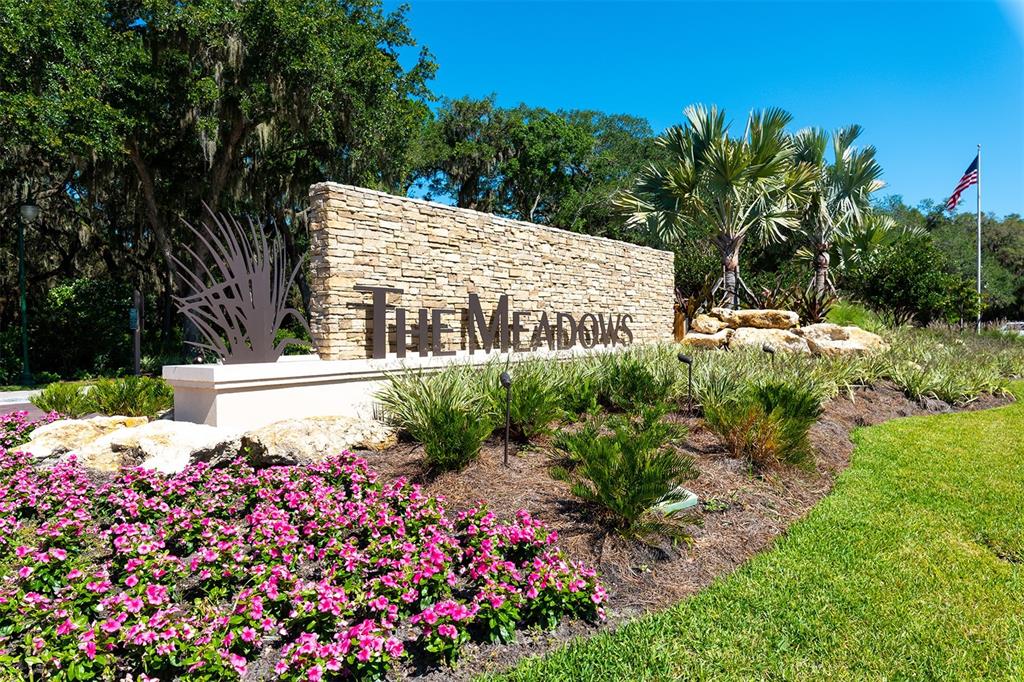 A stone monument sign reading The Meadows sits in a landscaped garden with pink flowers — 5315 MYRTLE UNIT 46, SARASOTA, FL