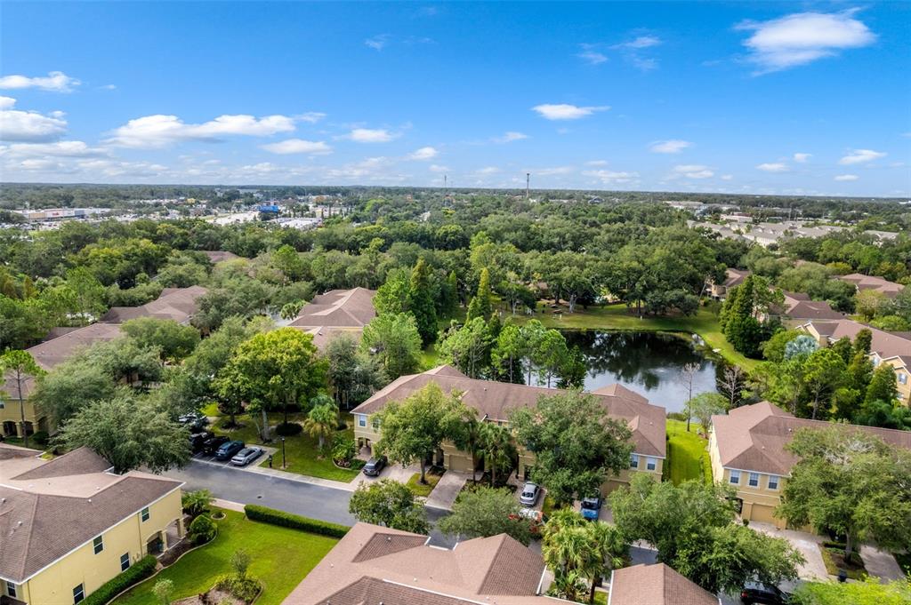 A pond sits in front of apartment buildings surrounded by trees under a blue sky — 9237 RIVER ROCK LANE, RIVERVIEW, FL